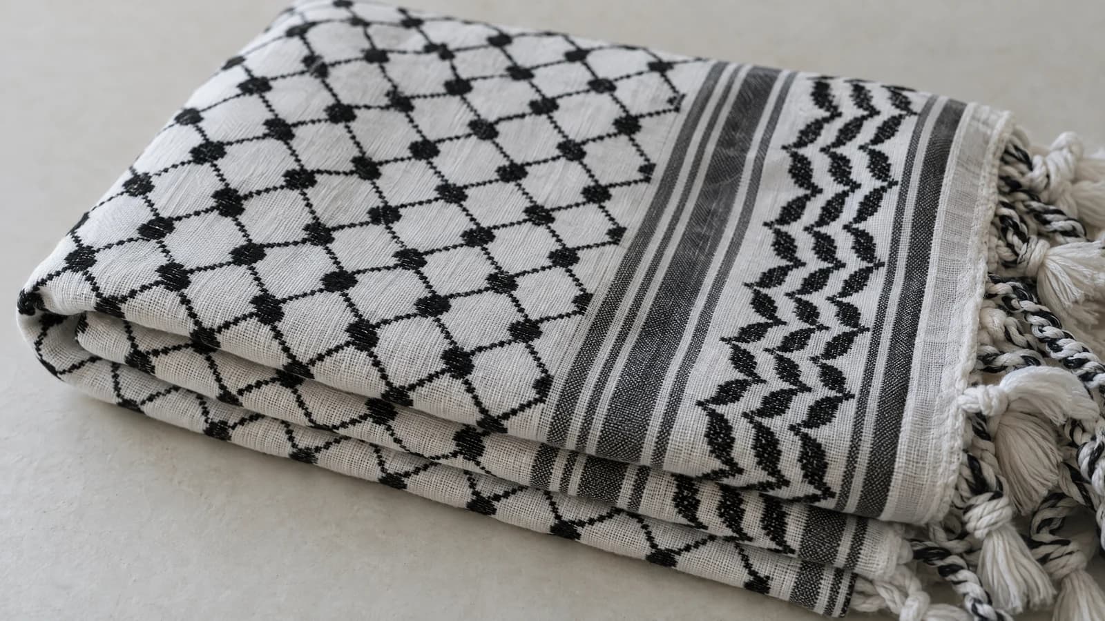 Traditional black-and-white Palestinian keffiyeh folded to show its woven pattern and fringed edge.